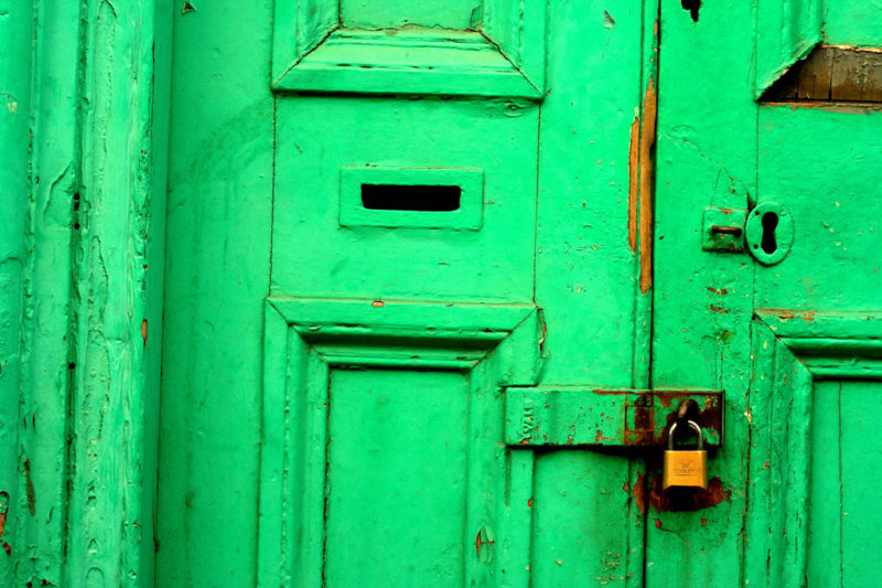 A green exterior door is sealed with a padlock.