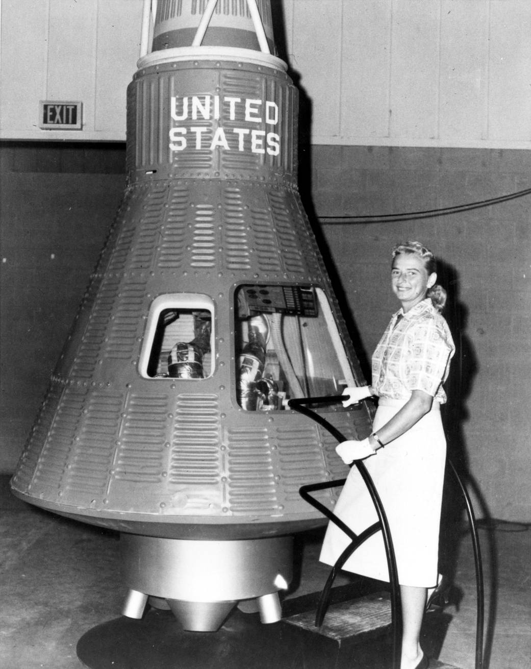 Jerrie Cobb, one of the "Mercury 13," poses next to a Mercury spaceship capsule. 