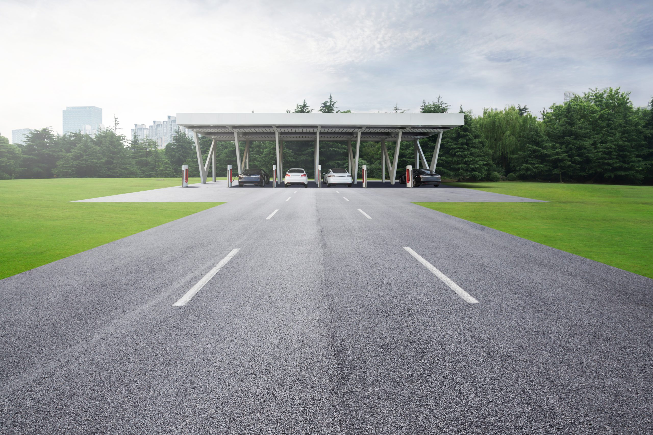Electric cars charging at a covered chargepoint surrounded by grass.