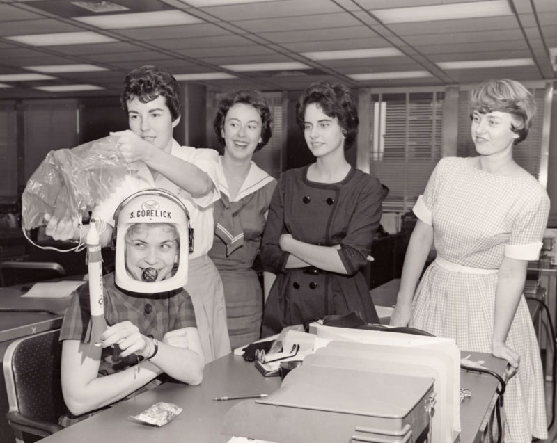 Black-and-white photo of young women joking around in an office.