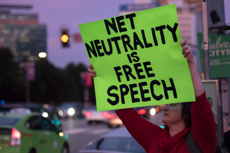 A woman outside a federal building in Los Angeles holds a placard stating 