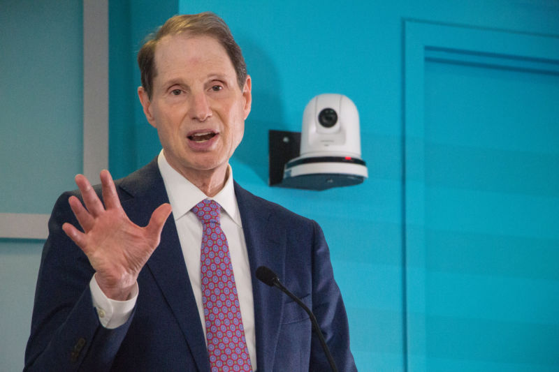 A man in a suit talks in front of a security camera