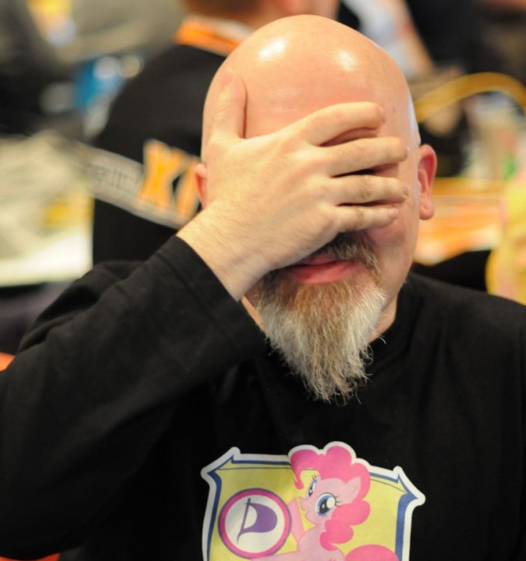 Image shows a man with a pony hoodie doing a facepalm.