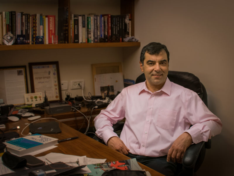 A smiling man sits at a desk.