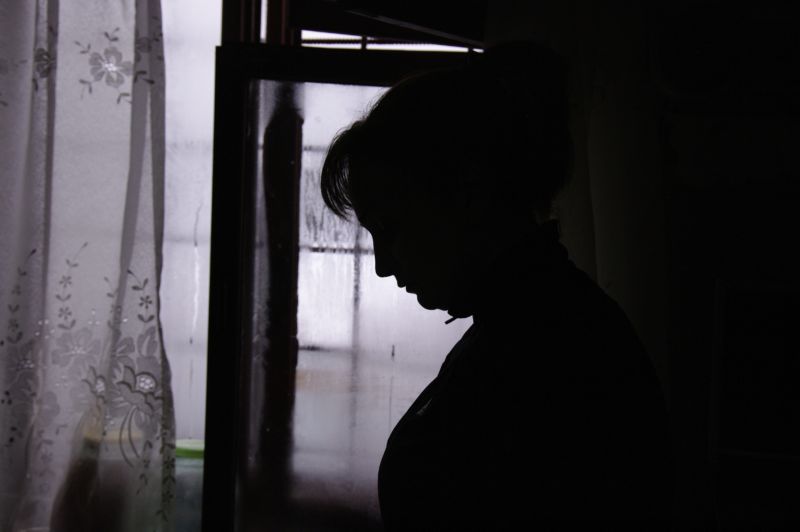 A shadowy figure of a woman in front of a window.