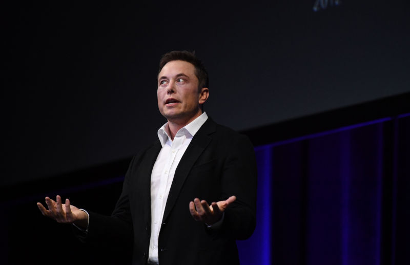 Elon Musk gives a talk on a stage.