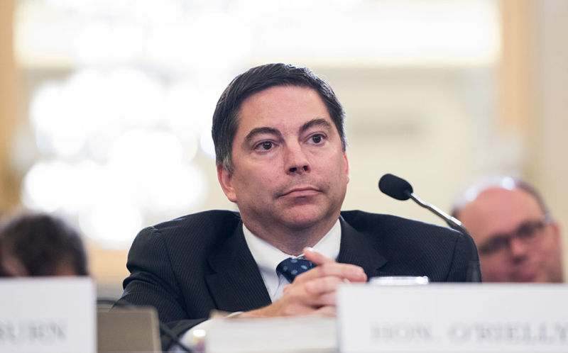 FCC Commissioner Michael O'Rielly sitting at a table in front of a microphone during a Senate committee hearing.