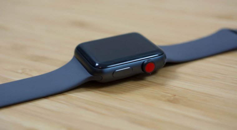 Close-up photo of a black smartwatch on a wood table.