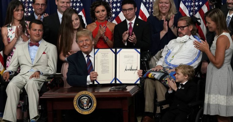 President Trump holds up the right to try act after his signing, surrounded by supporters.