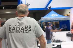 A man with a shirt reading "You can't be a badass wearing a leash"