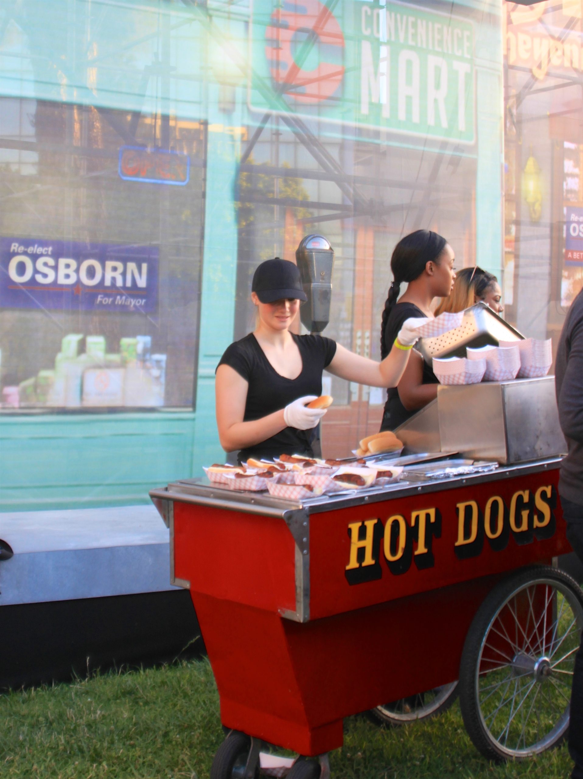 A woman serve hot dogs from a cart