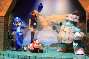 A woman poses with Mega Man 11 statuary