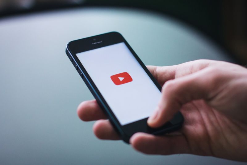 A person's hand holding a smartphone that displays the YouTube app.