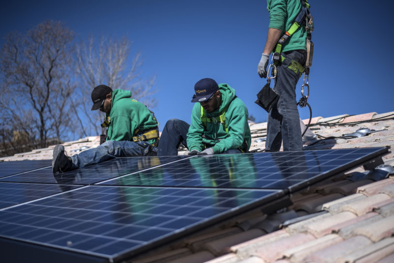 Workers secure solar panels to a rooftop during a SolarCity Corp. residential installation in Albuquerque, New Mexico, on Monday, February 8, 2016.