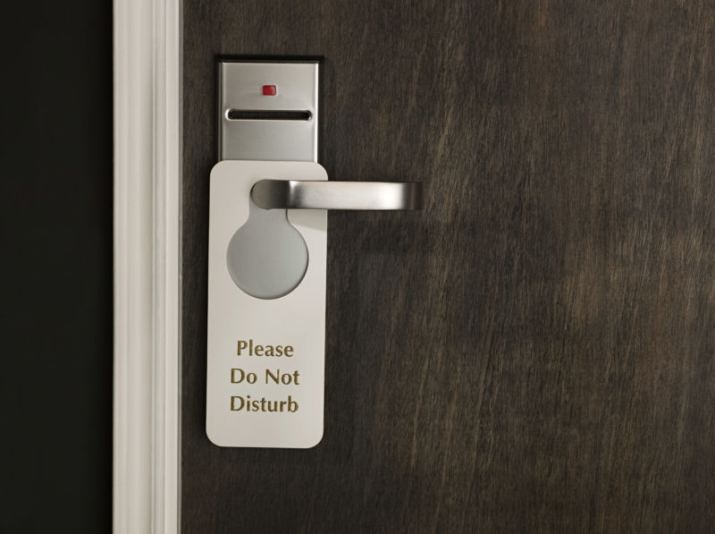 A hotel room door with a sign reading 