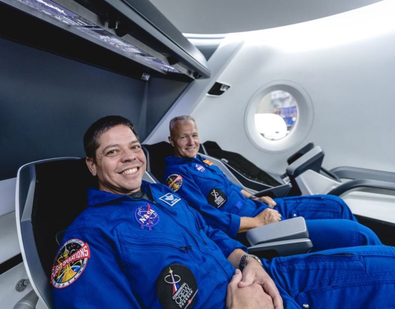 Two men in jumpsuits seated.