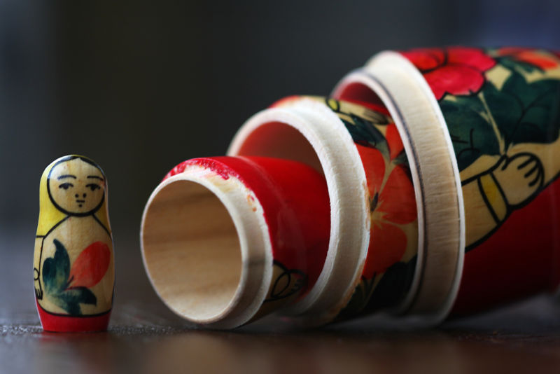 A set of Matryoshka dolls. To the smallest doll is upright and looking back at the bottoms of all the other dolls, which are still together.