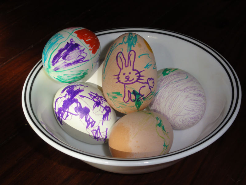 Picture of a white bowl holding several hand painted easter eggs.