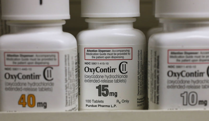 Consumer-sized bottles of prescription drugs sit on a shelf.