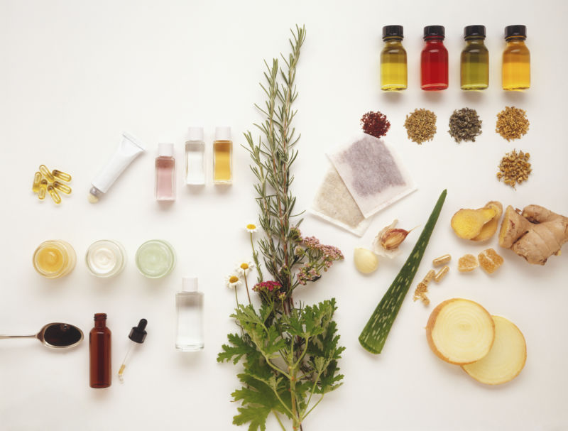 Bottles of herbal oils and dried plants used in alternative medicine.