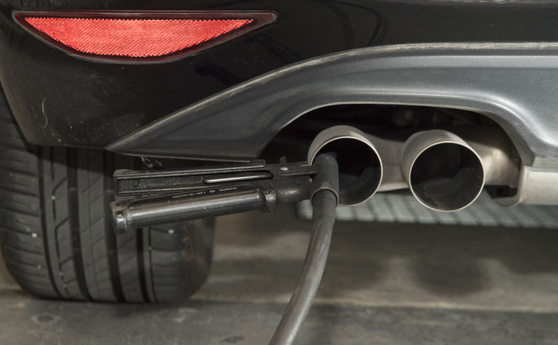 A tube attached to the tailpipe from a sports car performs an emissions test.