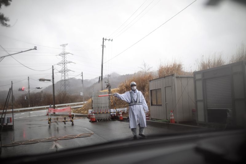 Man in protective gear gesturing outside Fukushima prefecture