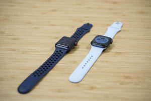 An Apple Watch Series 4 next to an Apple Watch Series 3 on a wooden table.