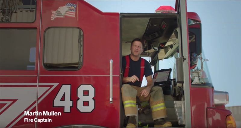A firefighter sitting in a fire truck and talking.