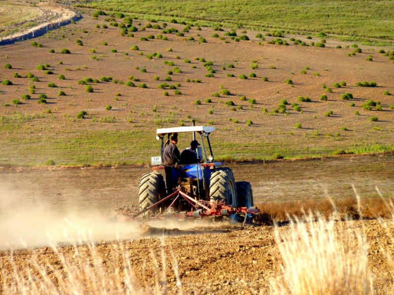 Image of a tractor sending dust into the air while plowing a field.