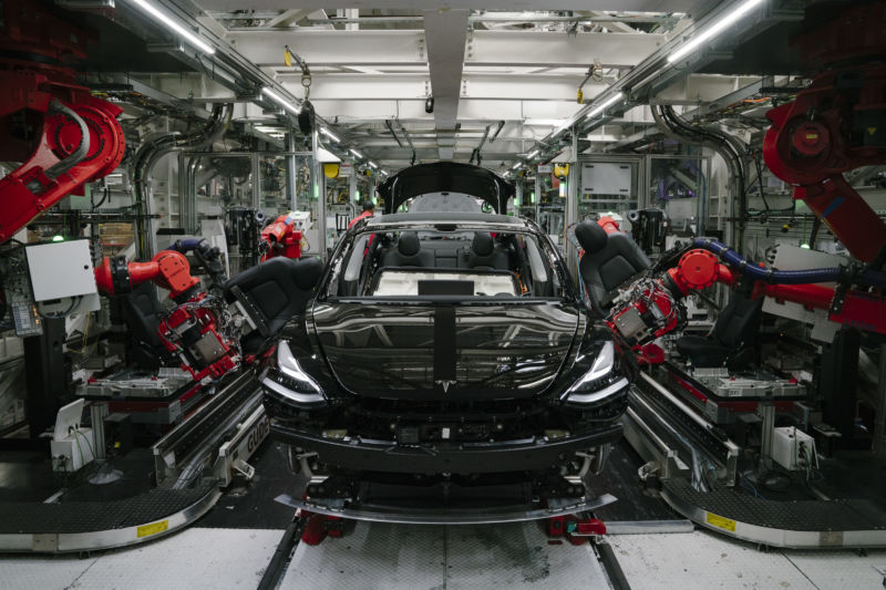 Robotic arms install the front seats to a Model 3 at the Tesla factory in Fremont, California.