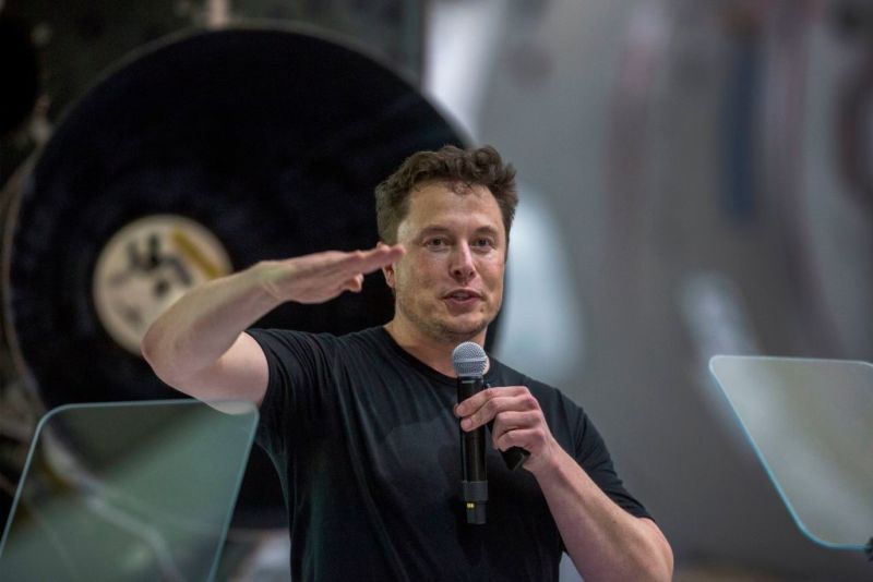 Elon Musk sits near a Falcon 9 rocket during his announcement that Japanese billionaire Yusaku Maezawa will be the first private passenger to fly around the moon aboard the BFR launcher.