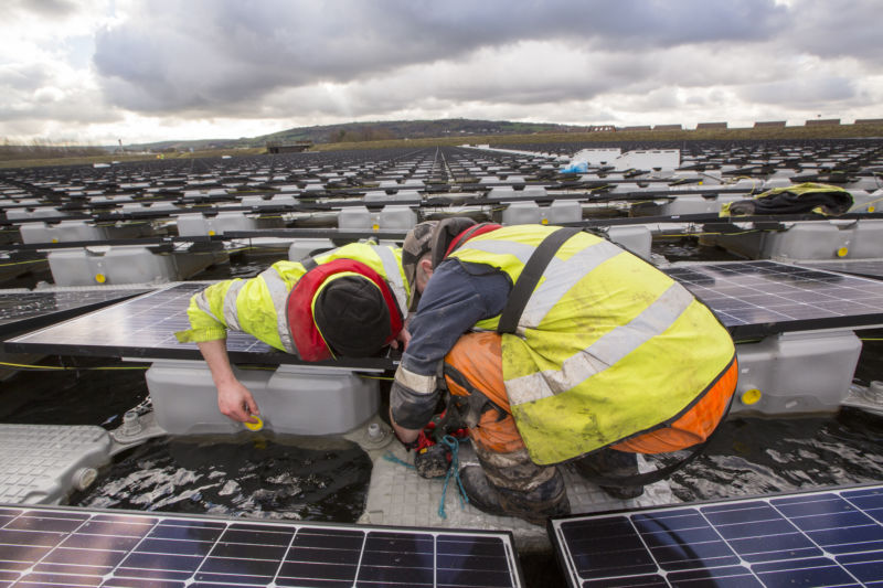 Two people working on a floating solar installation