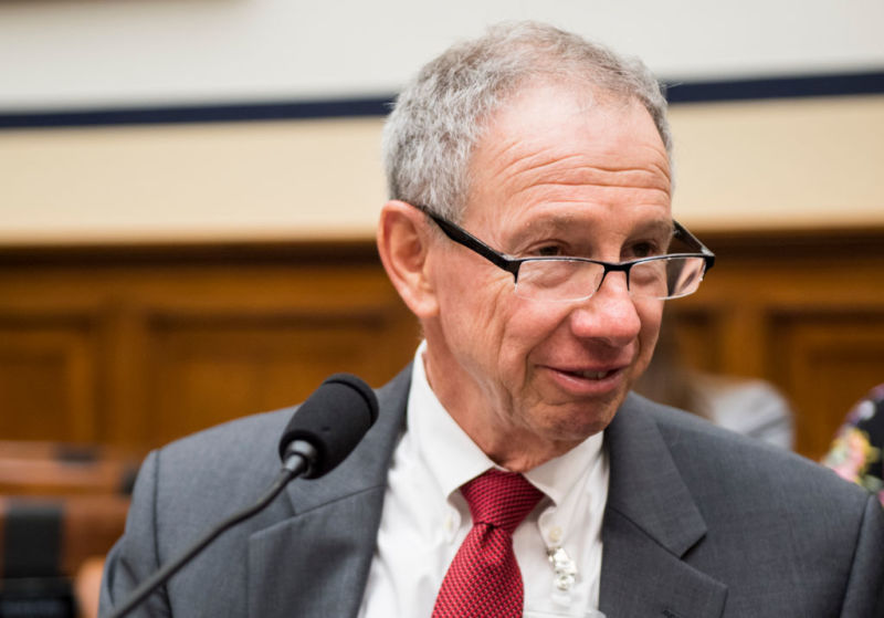 A man in a suit speaks in a microphone.