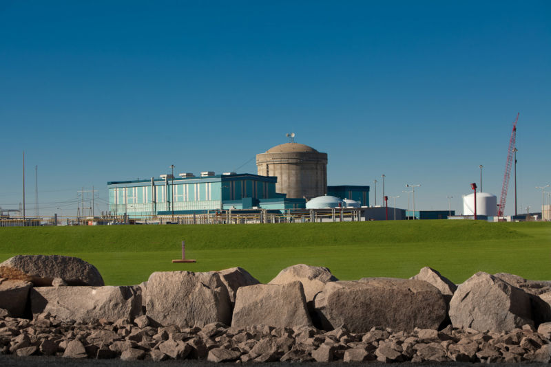 A nuclear plant in a grassy field during the summer.