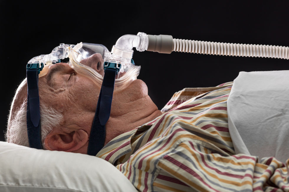 Man sleeping, using a mask for sleep disorder treatment.