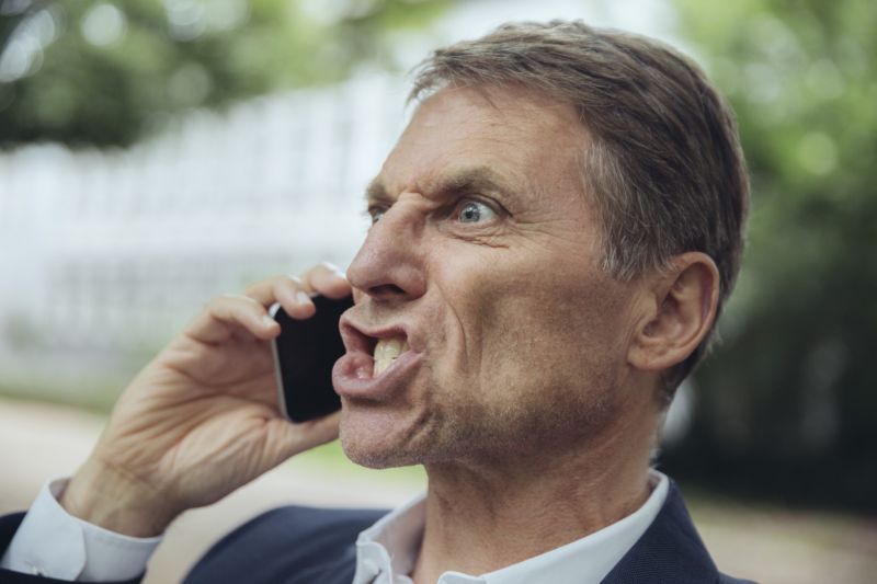 An angry man yelling into a cell phone.