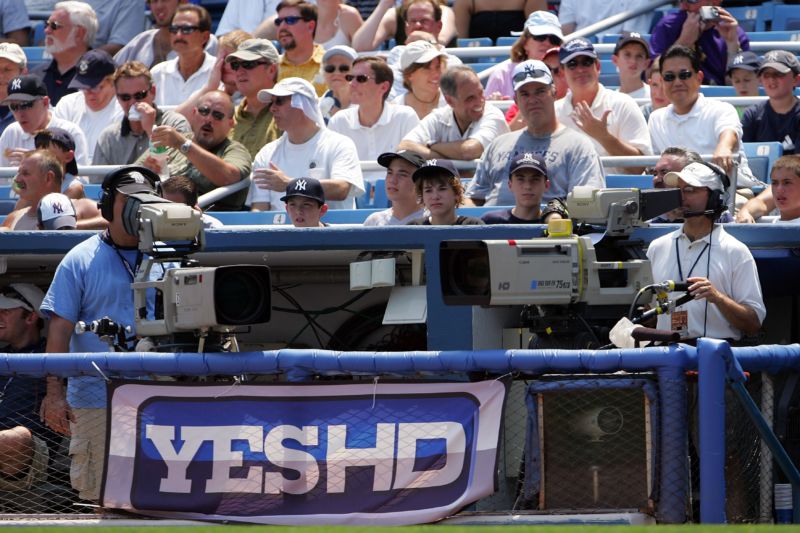 TV cameramen and a YES network logo banner at Yankee Stadium.