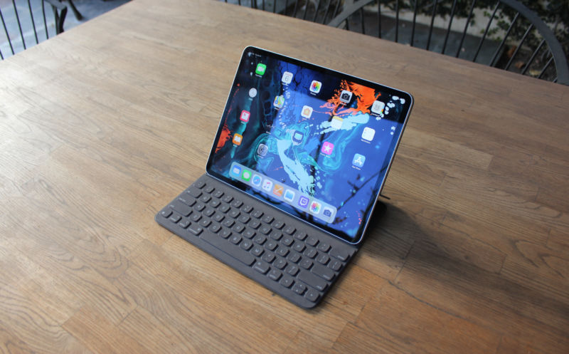 A tablet with a keyboard sits on a wooden table.