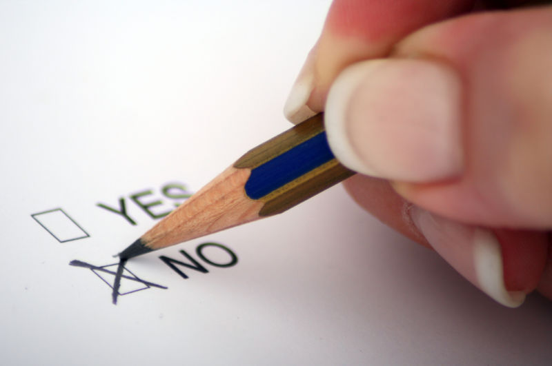 A person's hand holding a pencil and marking an X in a box labeled, 