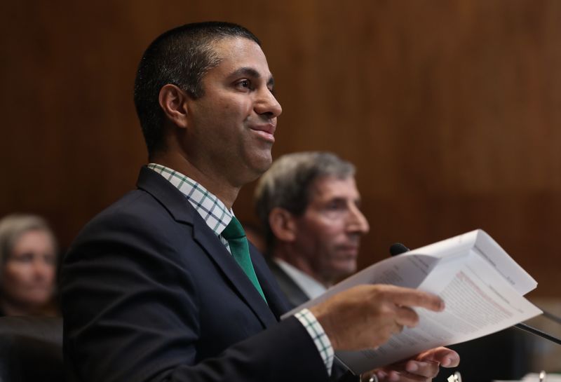 FCC Chairman Ajit Pai holding a stack of papers while testifying in front of a Senate committee.