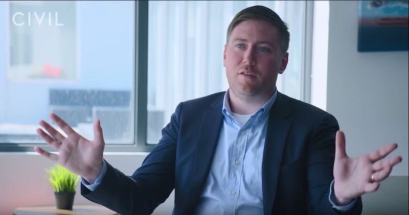 A man in a blazer gives an interview.