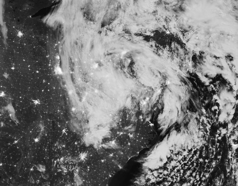 Black-and-white satellite photograph of storm clouds over land and ocean.