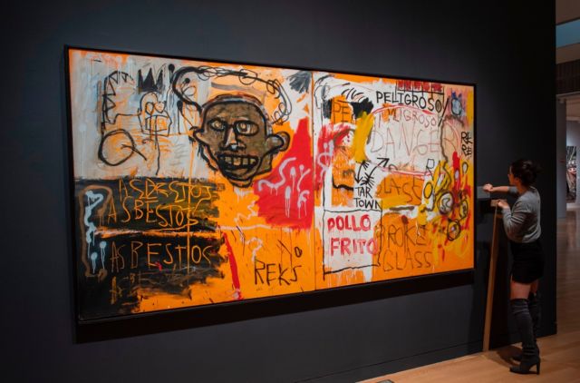 A Sotheby's employee hangs a name plate near Jean-Michel Basquiat's <em>Untitled (Pollo Frito)</em> on November 2, 2018, at Sotheby's Auction house in New York.