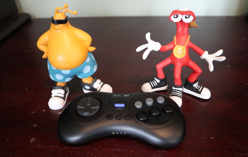 The 8Bitdo M30, posed next to a pair of Toejam and Earl figurines that shipped to select Kickstarter backers.