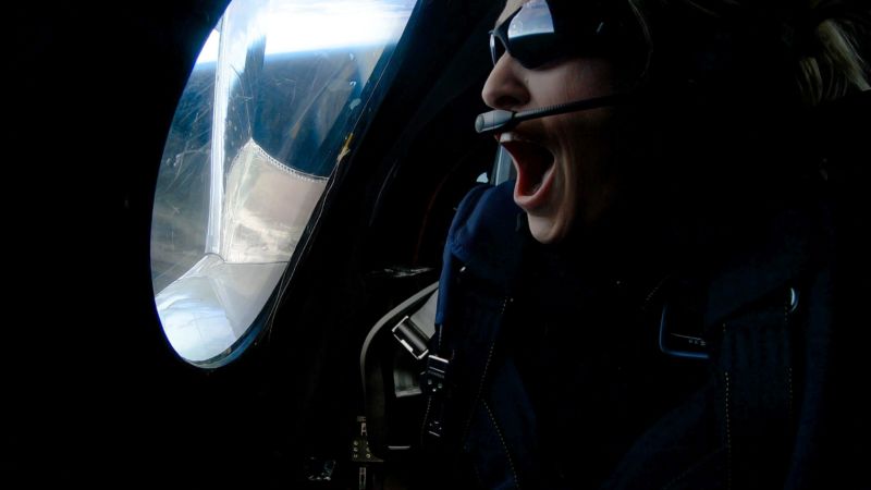 Excited passenger of a space capsule looks out window.