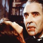Still image from a Hammer horror film in which a vampire (Christopher Lee) sucks blood from an attractive female victim.