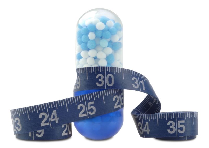 Illustration of a diet pill with a measuring tape wrapped around it.