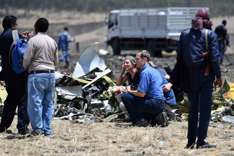 Relatives of the victims of the Sunday plane crash take a picture next to a pile of airplane fuselage at the crash site of the Ethiopian Airlines operated Boeing 737 MAX aircraft, at Hama Quntushele village in the Oromia region, on March 13, 2019. - A Nairobi-bound Ethiopian Airlines Boeing crashed minutes after takeoff from Addis Ababa on March 10, 2019, killing all eight crew and 149 passengers on board, including tourists, business travelers, and "at least a dozen" UN staff. Families of the victims were taken to the remote site on March 13, 2019, where the plane smashed into a field with 157 passengers and crew from 35 countries, leaving a deep black crater and tiny scraps of debris. 