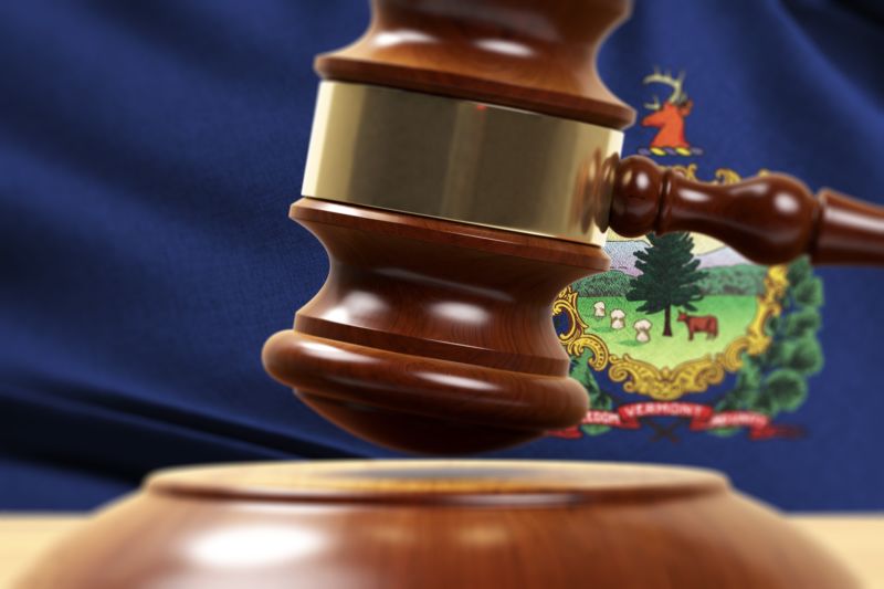 Illustration of a judge's gavel in front of Vermont's state flag.