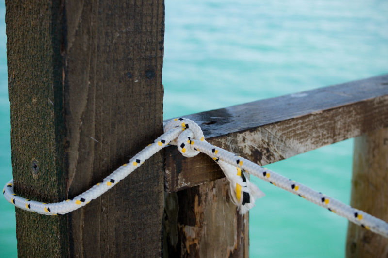 Rope lashed to a wooden port next to water.